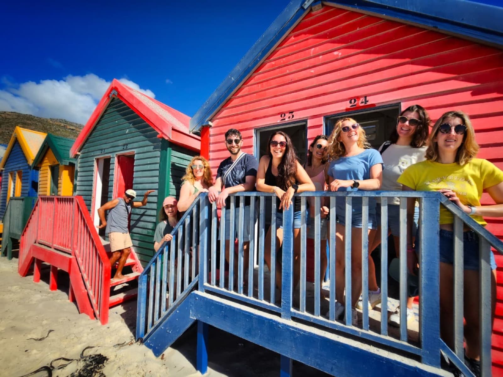 Un groupe de voyageurs devant les cabines colorées de Muizenberg, Le Cap