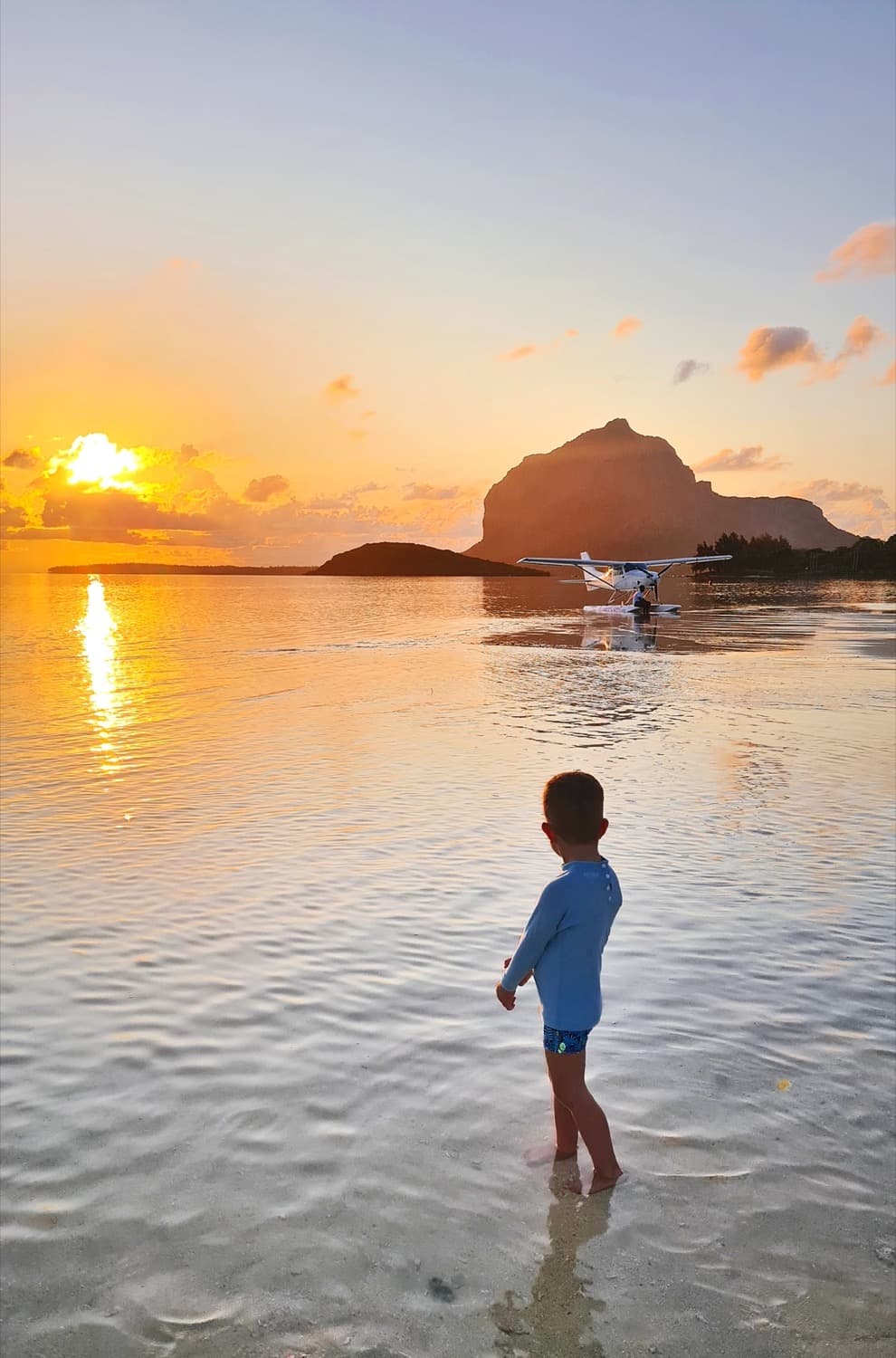 Un enfant joue dans l'eau au coucher du soleil face au Morne, île Maurice